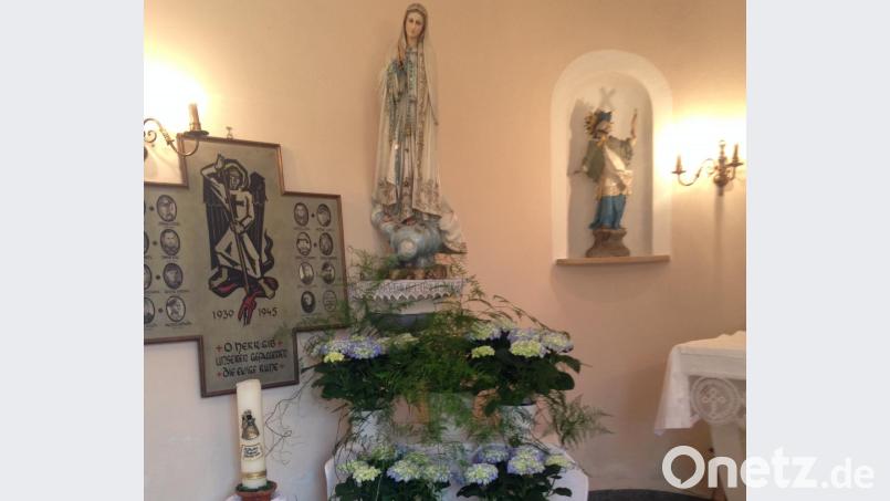 Hortensien mit hellblauen und weißen Blüten stehen zu Füßen der Marienstatue als Zeichen gelebter Verehrung. Bild: fjo