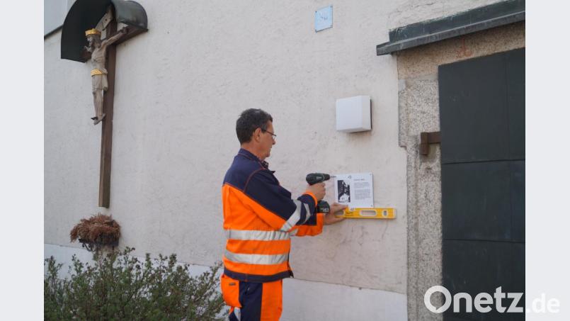 Gemeindearbeiter Karl Bodensteiner bringt die Info-Tafeln an den historischen Gebäuden der Gemeinde an. Hier erhält der Eingang der aus dem 12. Jahrhundert stammenden Jakobuskirche, die bis 1958 Pfarrkirche von Schirmitz war, ihr Hinweisschild. Bild: du