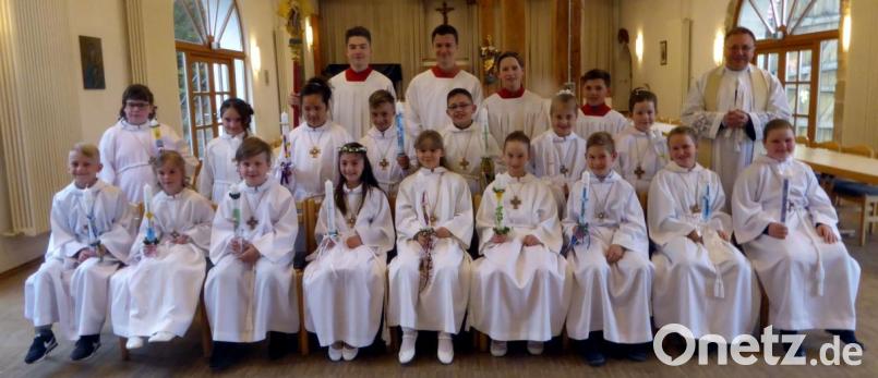 Albe, Kerze und Kreuz der Kommunionkinder stellt Pfarrer Markus Bruckner (hinten rechts) einer Berufskleidung für getaufte Christen gleich. Bild: exb