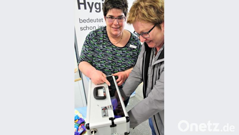 Der Koffer mit Schwarzlicht, den Hygienefachkraft Sabine Pühl (links) mitgebracht hat, fördert zutage, ob wirklich die ganze Hand desinfiziert worden ist. Bild: stg