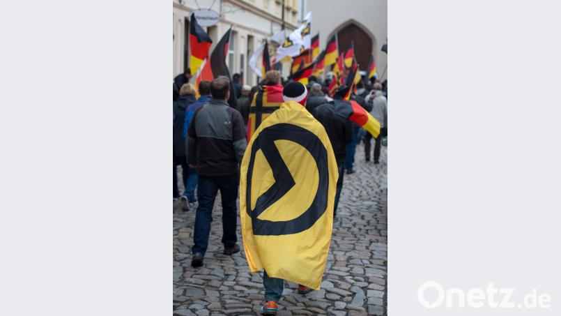 Ein Mann mit einer Fahne mit dem Logo der "Identitären Bewegung" bei einer Demo in Sachsen. Bild: Arno Burgi/dpa