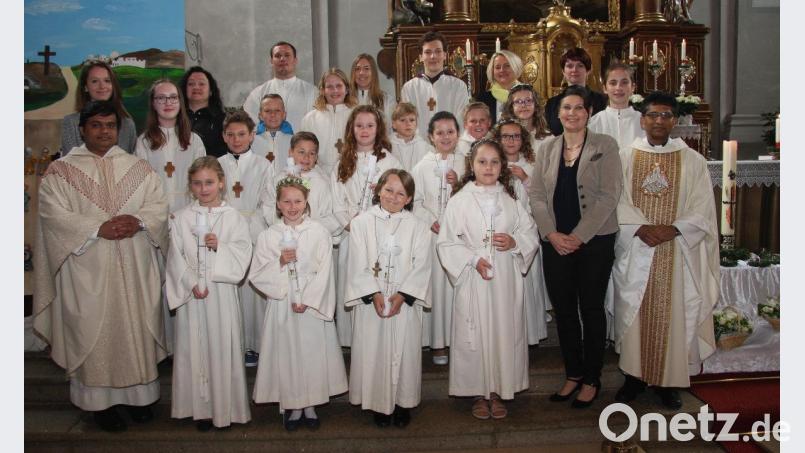 Den Kommuniongottesdienst gestalteten Pfarrer Joseph (rechts) und Pater Martin (links) gemeinsam. Gekommen waren auch die Rektorin der Grundschule Wiesau, Inge Dick (vorne, Zweite von rechts), und die Lehrerin der dritten Klasse, Julia Greger (hinten links). Es gratulierten auch die Ministranten und die Tischmütter. Bild: wro
