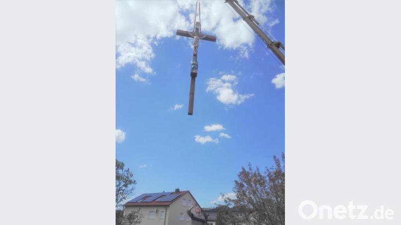 Ein Kranwagen hievt das imposante Holzkreuz in der Neuenhammerstraße wieder an seinen angestammten Platz. Bild: tu