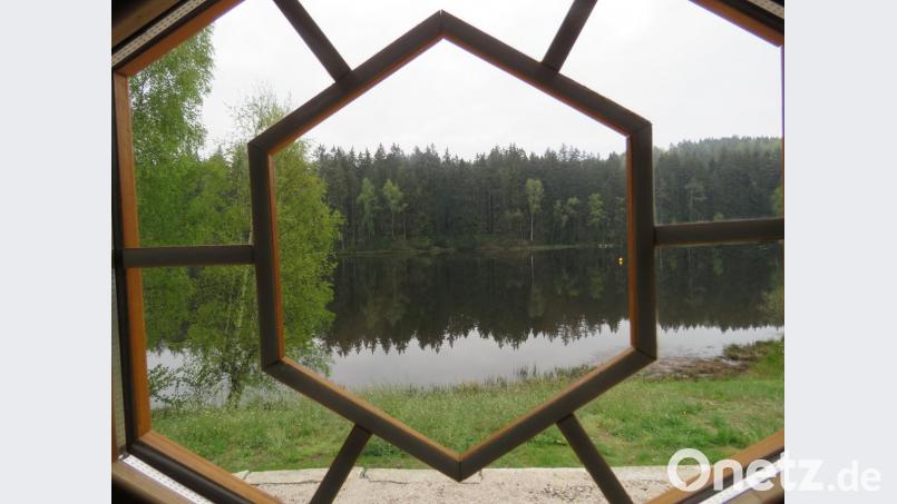 Am frühen nächsten Morgen weht kein Lüftchen. Durchs Türfenster bietet sich ein idyllisches Naturschauspiel: Der Wald gegenüber spiegelt sich auf der glatten Wasseroberfläche. Bild: ubb