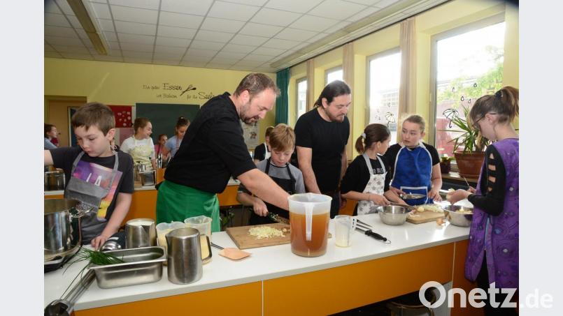 &quot;Chefkoch&quot; Andreas Meier (links) und Schulleiter Andreas Koblen, Bor, bereiten mit Unterstützung der Kinder das Menü vor. Bild: bey