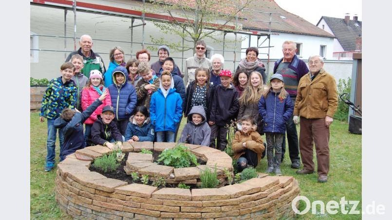 Die eifrigen Kinder der Klasse 3b helfen, den Garten des Mehrgenerationenhauses auf Vordermann zu bringen. Ihre Lehrerin Ingrun Allwartt (Dritte von rechts), die Senioren sowie Aktionsleiterin Elisabeth Gottsche (Zweite von links) freuen sich über den Fleiß der Schüler. Bild: az
