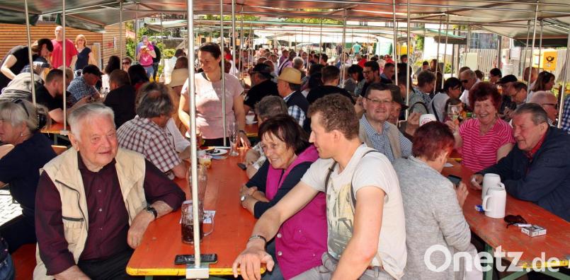Dicht gedrängt sitzen die Besucher unter den schattenspendenden Zeltplanen auf dem Dorfplatz. Bild: zer