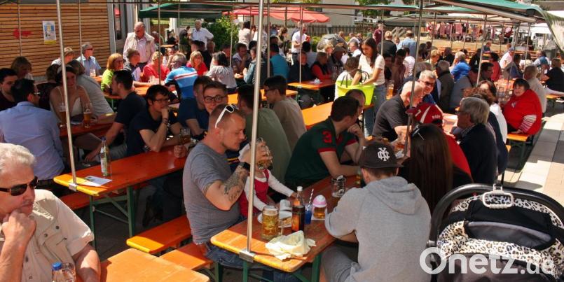 Dicht gedrängt sitzen die Besucher unter den schattenspendenden Zeltplanen auf dem Dorfplatz. Bild: zer