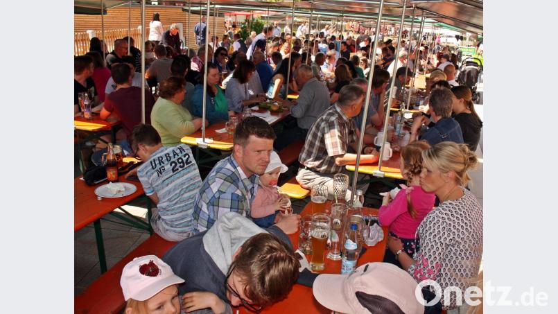 Dicht gedrängt sitzen die Besucher unter den schattenspendenden Zeltplanen auf dem Dorfplatz. Bild: zer