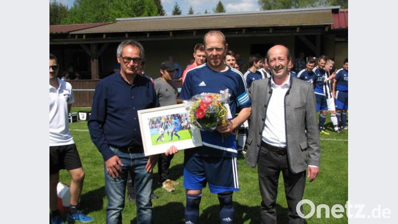 Mit einem Blumenstrauß und einer Bildaufnahme von ihm in Aktion verabschiedeten die Vorsitzenden des VfB Mantel Richard Paulus (rechts) und Max Herrmann (links) den langjährigen Spieler und Kapitän Stefan Prölß (Mitte). Bild: knh