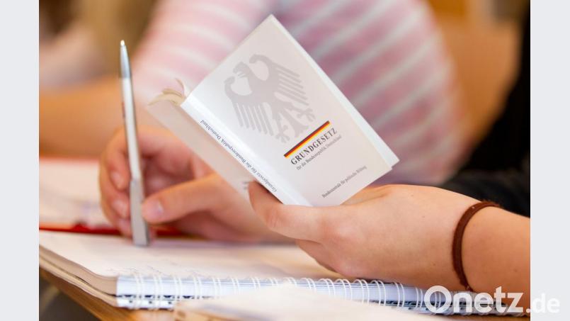 Eine Jura-Studentin hält in einer Vorlesung an der Universität eine Ausgabe vom Grundgesetz. Bild: Friso Gentsch/dpa