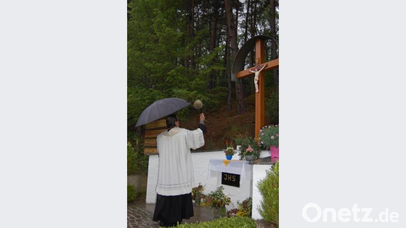 Die geschmückte, insgesamt aufgefrischte Anlage mit dem neuen Kreuz an den Totenbrettern in der Felsmühlstrraße. Stadtpfarrer Bernhard Müller segnet vorab der Maiandacht das Kreuz. Bild: az