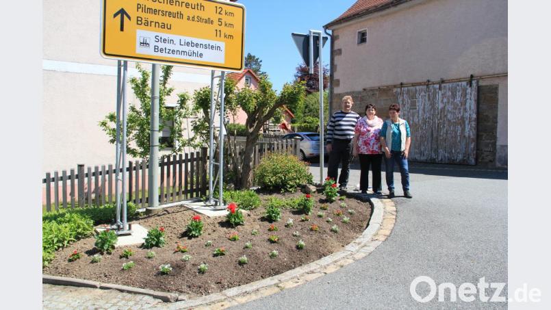 Martina Ott und Rita Trißl (von rechts) pflanzten zusammen mit OGV-Vorsitzendem Jörn Schedl (links) an Beeten und Pflanztrögen wie hier in der Hauptstraße wieder verschiedene Blumen an - heuer in den Feuerwehrfarben Rot und Weiß, extra für das Feuerwehrjubiläum. Bild: flt