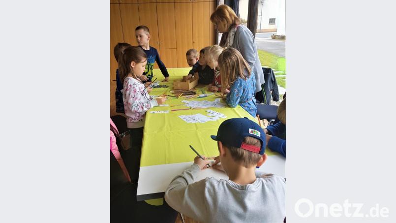 Die Kinder blättern eifrig in dem großen Bücherangebot und gestalten eigene Lesezeichen für die ausgeliehenen Bücher. Bild: jml