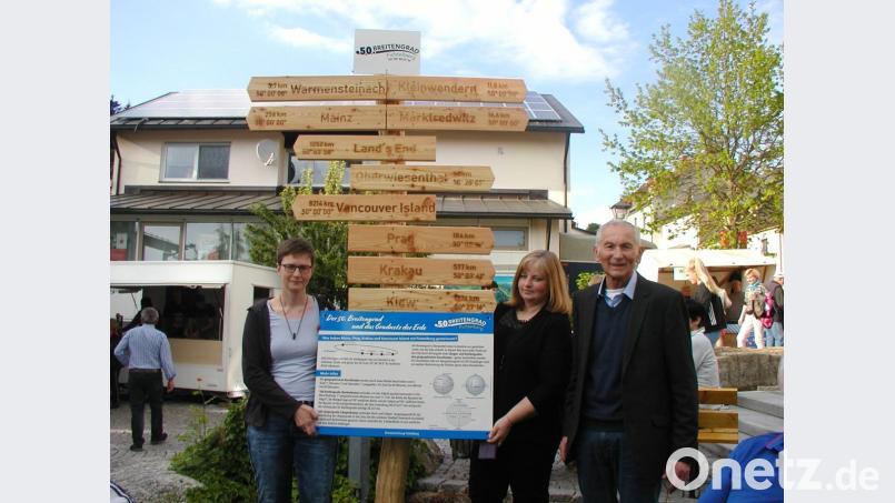 Sprecherin Manuela Hornung und Christina Braun von der Ortsentwicklungsgruppe sowie zweiter Bürgermeister Karl Heinz Glaser (von links) präsentieren beim Dorffest den neuen Schilderbaum und die Infotafel zum 50. Breitengrad. Bild: gis
