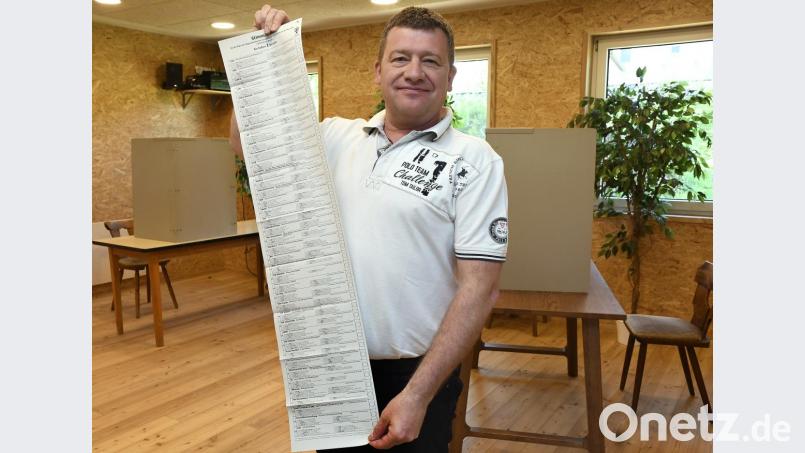 Peter Zirnstein zeigt im Wahllokal im Dorfstodl in Moos, wie lang der Stimmzettel zur Europawahl mit den 40 Parteien ist. Bild: Petra Hartl