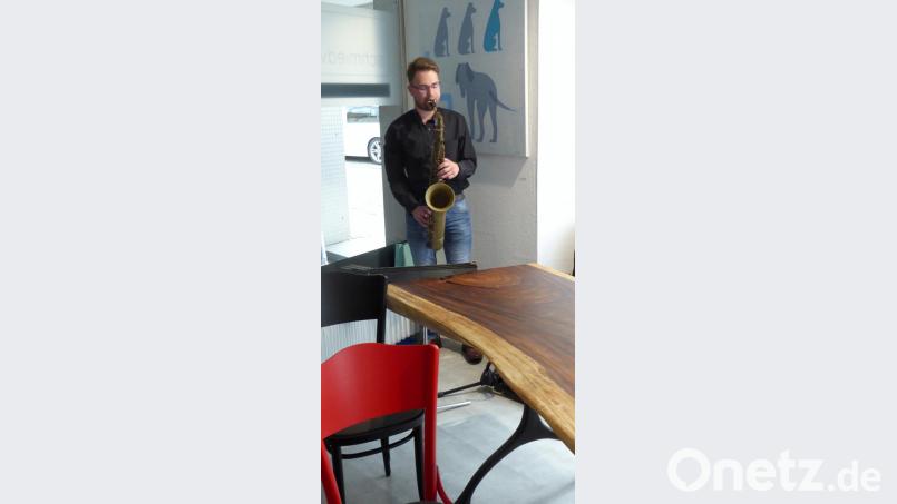 Saxofonist Daniel Šatra vor dem Ölgemälde „Hundeschule“ und vor einem Tisch aus Akazienholz und Gusseisengestell. Bild: fsb