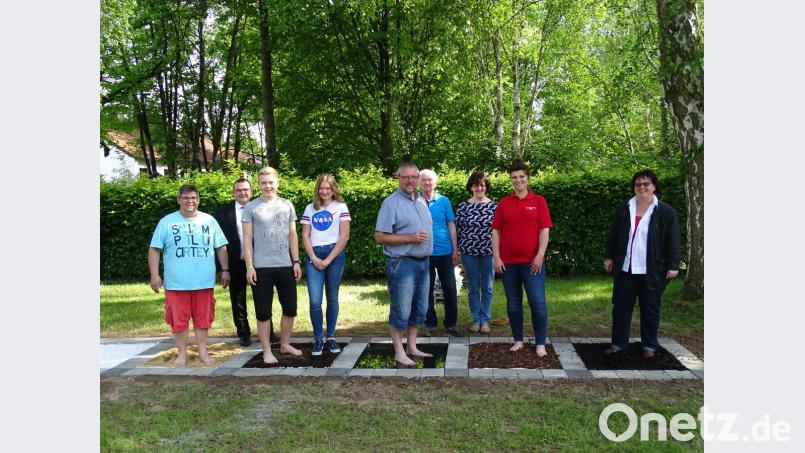Heimleiterin Claudia Heier und Tanja Weiß, stellvertretende Leiterin der Tagespflege (von rechts), danken Jochen Gößl (links) und seinen Helfern für den neuen Barfußpfad. Bild: jzk