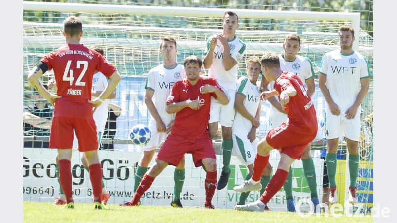 Der Rosenheimer Pius Krätschmer (vorne) zirkelt einen Freistoß an der Gebenbacher Abwehrmauer vorbei auf das Tor von Michael Nitzbon. Bild: Hubert Ziegler