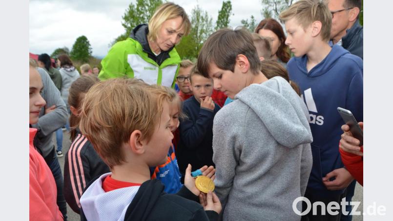 Reihum dürfen die Kinder der Zottbachtalschulen die Olympia-Goldmedaillen in den Händen halten. Fast ehrfürchtig blicken die Buben und Mädchen auf diese sportliche Auszeichnung von Heike Drechsler (Mitte). Bild: dob