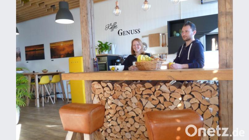 Die Kaffeebar zwischen den zwei Großraumbüros ist ein beliebter Treffpunkt. Rechts schließt sich eine gemütliche Couch-Lounge mit Schwedenofen an. Sandra und Sebastian genießen die kurze Pause bei einem Cappuccino. Diesen sponsert die Firma zum Wohlfühlambiente dazu.