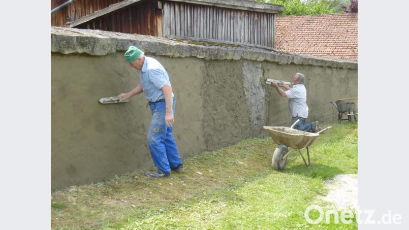 Mit Auge und Geschick bringen die Helfer den Putz auf der Mauer auf. Bild: mad