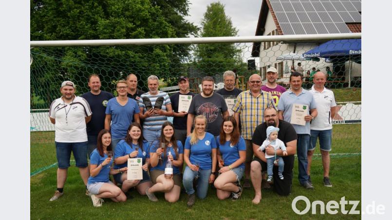 Stolz zeigte Rotkreuz-Team-Kapitän Günter Plonner (hinten, Fünfter von links) seine Pantoffeln, die er beim Seilziehen trug. Die drei erstplazierten Herrenteams erhielten Zoigl-Gutscheine und die siegreiche Damenmannschaft eine Jumbo-Sektflasche. Vorsitzender Manfred Bauer (rechts) und zweiter Vorsitzender Daniel Grillmeier gratulierten den Teams. Bild: Sebastian Bötzl/exb
