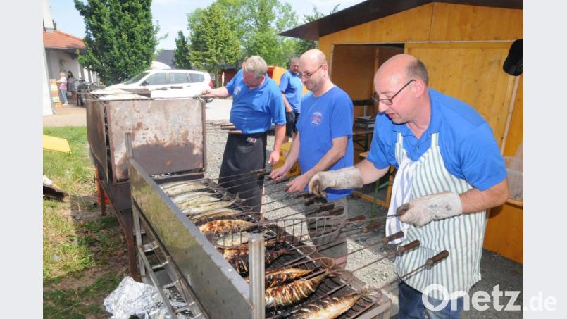 Im Vordergrund schwitzen die Vereinsmitglieder am Holzkohlengrill um die Wette, im Hintergrund warten die Gäste geduldig auf eine gegrillte Makrele. Bild: bey