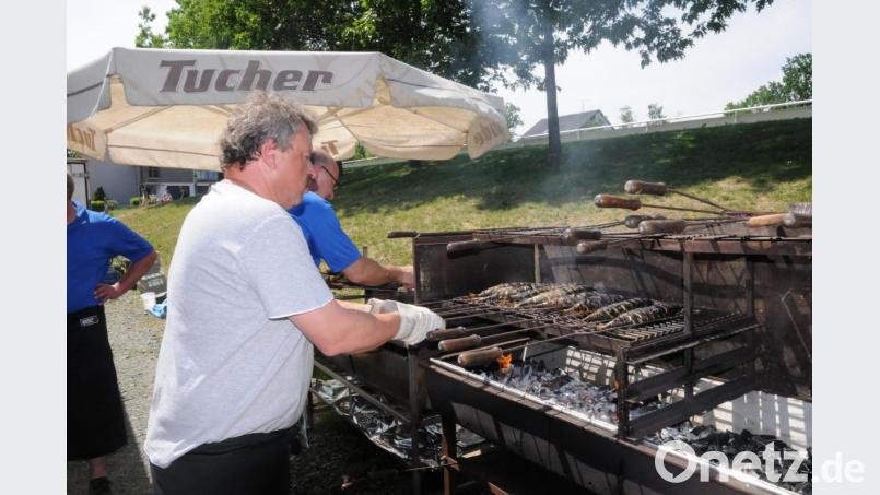 Im Vordergrund schwitzen die Vereinsmitglieder am Holzkohlengrill um die Wette, im Hintergrund warten die Gäste geduldig auf eine gegrillte Makrele. Bild: bey