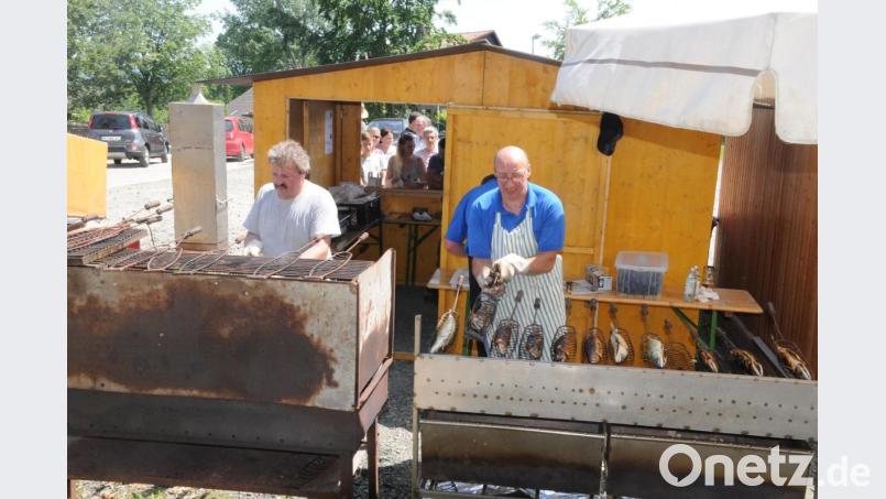 Im Vordergrund schwitzen die Vereinsmitglieder am Holzkohlengrill um die Wette, im Hintergrund warten die Gäste geduldig auf eine gegrillte Makrele. Bild: bey