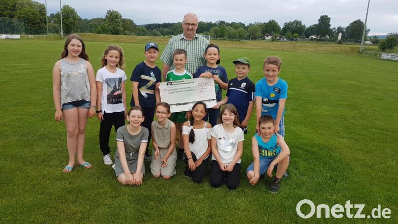 Zwölf Erstkommunionkinder der Pfarrei Moosbach spenden auch im Namen ihrer Eltern 1555 Euro an die Kinderkrebshilfe Nordoberpfalz. Vorsitzender Herbert Putzer nimmt die Spende dankbar entgegen. Bild: gi