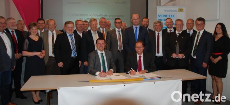 Landrat Thomas Ebeling (vorne links) und Josef Scherl von der Telekom unterschreiben den Kooperationsvertrag zum Breitbandausbau in 18 Kommunen. Neben den Bürgermeistern waren Staatsminister Albert Füracker (Achter von rechts) und MdB Karl Holmeier (Sechster von rechts) anwesend. Bild: Portner