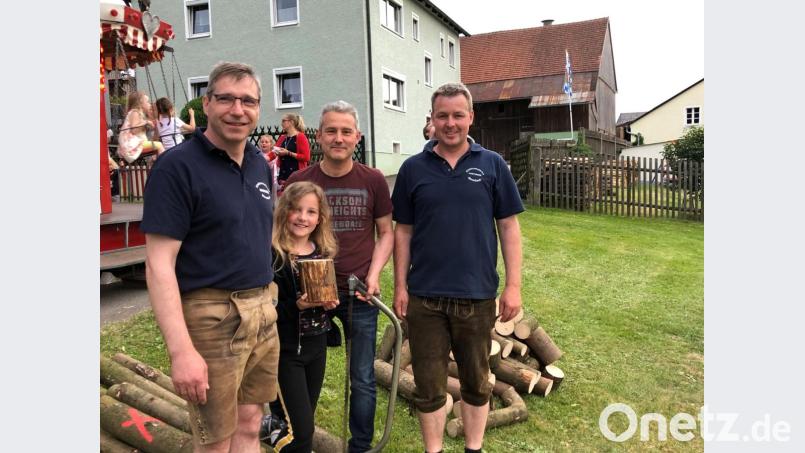 Die neunjährige Julia Liegl hat es geschafft ein Holzstück mit genau 1000 Gramm abzusägen. Dazu gratulierte ihr Vater und 2. Kommandant Christian Bayerl (rechts) und Vorsitzender Hermann Ach (links). Bild: gi
