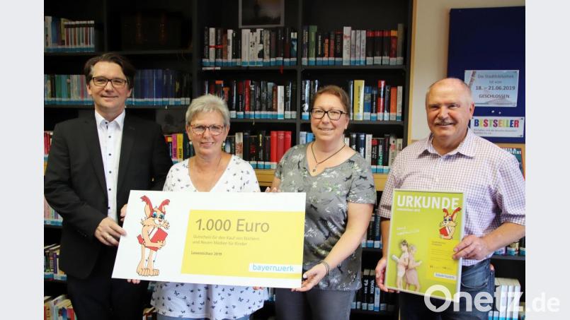Aus den Händen von Markus Windisch nehmen Renate Schneider und Leiterin Petra Danzer das mit 1000 Euro verbundene &quot;Lesezeichen&quot; für die Stadtbibliothek entgegen. Auch Bürgermeister Peter Lehr freut sich über die Auszeichnung. Bild: jma