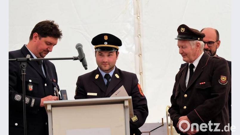 Kommandant Michael Roith und Kreisbrandrat Marco Saller von der Etzenrichter Feuerwehr übergeben die Urkunde und die Medaille des Deutschen Feuerwehrverbands an Ehrenkommandant Otto Waibl aus Algund. Bild: wlr