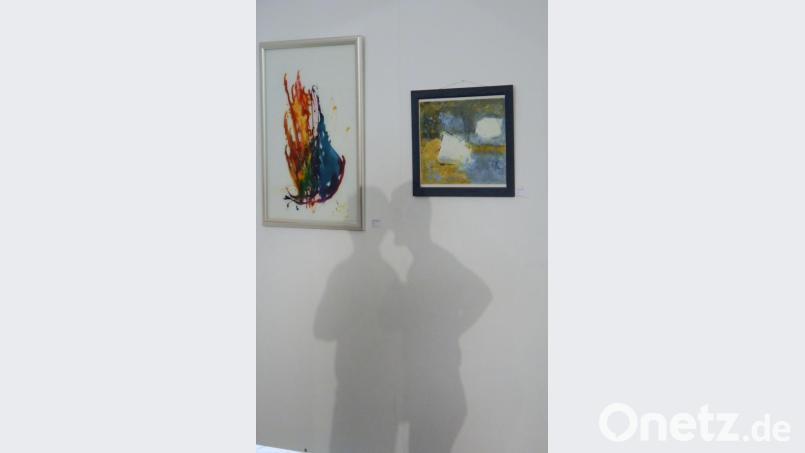 Zwei Besucher werfen einen Schatten, als wären sie selbst eine Skulptur. Das Bild links stammt von Carola Wittmann und heißt "Wiege des neuen Seins". Das Bild rechts "Stolperstein" hat Renate Ullmann angefertigt. Bild: Gabi Schönberger