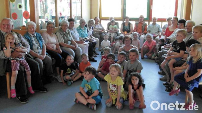 Kerstin Dilling (sitzend in der Mitte der Kinder), Josef Birkner (links), Lotte Zehrer (Fünfter von links) und Karl Pinzer (Zweiter von rechts) sowie die anderen Senioren und Kindergartenkinder freuen sich über den Besuch. Bild: hl