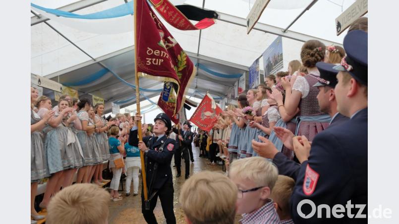 Die Fahnen der teilnehmenden Feuerwehren und Vereine werden von den Vorständen (rechts im Bild) und den Festdamen der Feuerwehr Zeinried (rechts) und des Patenvereins aus Teunz (links) begrüßt. Die endlose Schlange der einziehenden Fahnen macht spürbar, was Solidarität unter Feuerwehren und Vereinen ausmacht. Bild: tkr