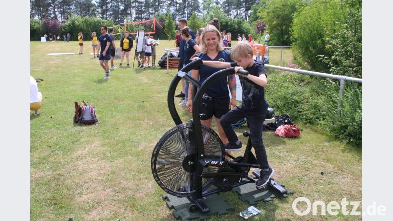 Carina Dippl von der Sparte Fitness zeigt einem Kind die Benutzung eines Air Bikes. Bild: sne