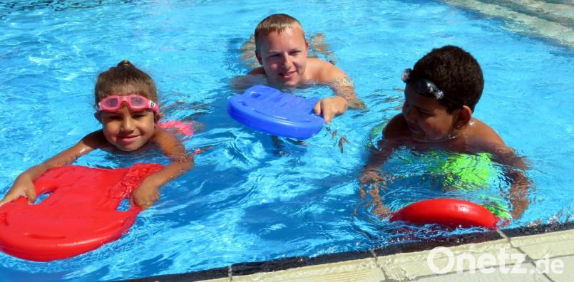 Hailey (6) und Deontoni (9) präsentieren dem Schwimmtrainer und Wasserwacht-Vorsitzenden Stefan Pelz stolz, wie gut sie bereits mit den Schwimmhilfen durchs Wasser kommen. Bild: ubb