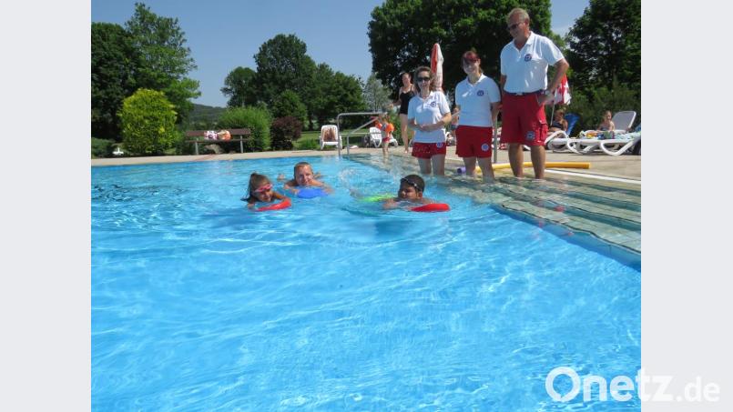 Stefan Pelz zeigt den Kindern Deontoni (9) und Hailey (6) den Umgang mit dem Schwimmbrett. Tamara, Nicole und Harald (draußen von links) schauen zu. Bild: ubb