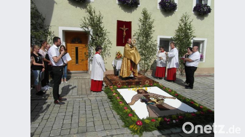 Am ersten Altar bei der Familie Hofmann spendet Pfarrer Heribert Stretz (Mitte) mit der Monstranz den Segen. Bild: hl