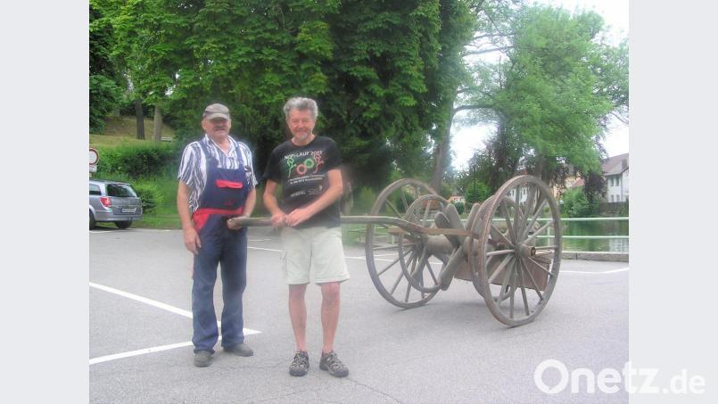 Die Ehrenmitglieder der Feuerwehr Erich Neuber (links) und Hans Walbrunn (rechts) beim Transport des über 100 Jahre alten Schlauchwagens in das Feuerwehrgerätehaus. Bild: tu