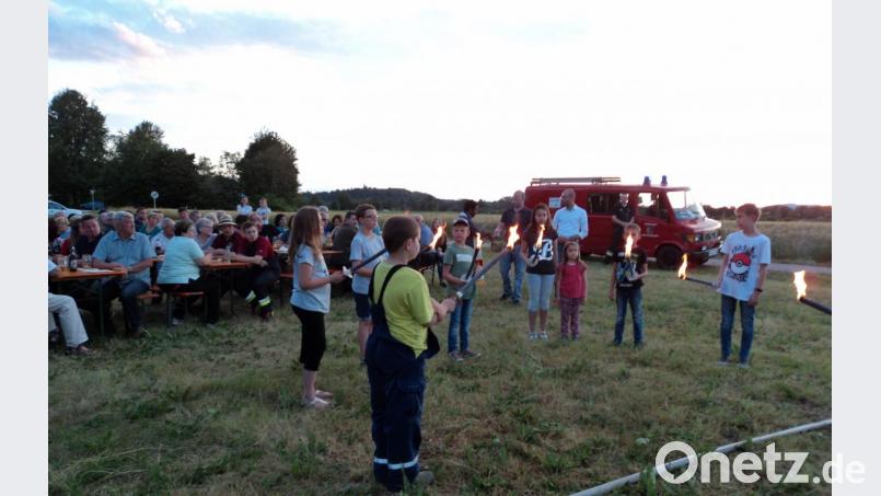 Mit Fackeln entzünden die Kinder den aufgeschichteten Holzhaufen. Bild: ksi