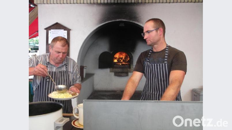 Alfons Troppmann (von links) und Stefan Gassner haben die Spezialitäten aus den Dorfbackofen frisch zubereitet und serviert - die Besucher waren wieder begeistert. Bild: trj