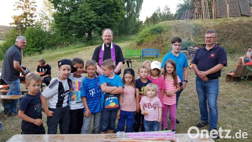Die Fackeln liegen schon bereit, mit denen die Kinder das Johannisfeuer entzünden. Zur Segnung des Feuers heißt Feuerwehrvorsitzender Markus Prechtl (rechts) Pfarrer Heribert Stretz (hinten Mitte) willkommen. Bild: hl