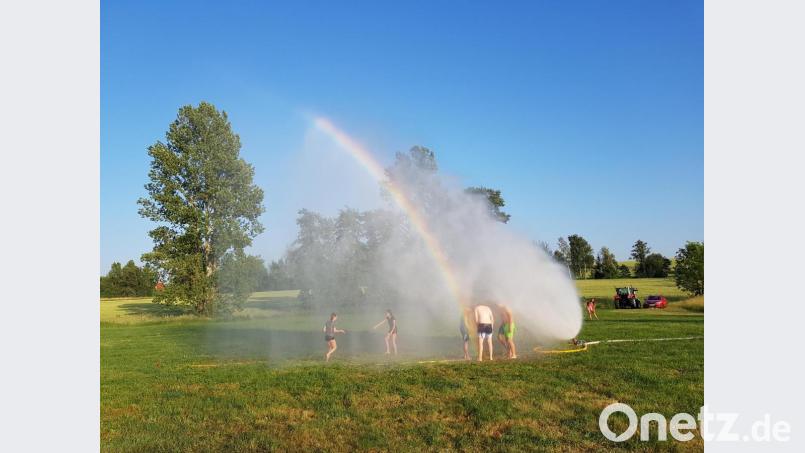 Abkühlung suchen einige Nachwuchsleute der Feuerwehr Altenstadt bei Vohenstrauß unterm Wasserstrahl des Feuerwehrschlauchs. Dabei bildet sich ein wunderschöner Regenbogen. Bild: ck