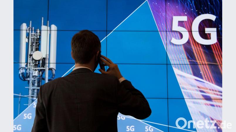 Ein Mann steht im Gebäude der Bundesnetzagentur vor einer Leinwand mit der Aufschrift 5G. Bild: Boris Roessler/dpa