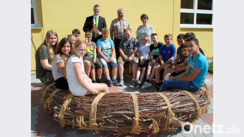 Schüler erproben die neue Weidensitzbank im Schulhof der Mittelschule. Im Hintergrund (von links) Michael Zinner, Marketing-Leiter der VR-Bank Niederbayern-Oberpfalz, Bürgermeister Markus Dollacker und Rektorin Helga Gradl. Bild: sön