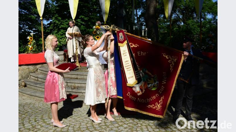 Festbraut Julia Beugler heftet das von Stadtpfarrer Pater Hans Ring gesegnete Fahnenband an die Fahne der Pleysteiner Wehr an. Bild: bey